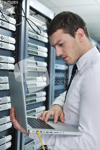 Image of businessman with laptop in network server room