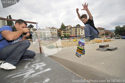 Image of Man taking photo of boy skating in park