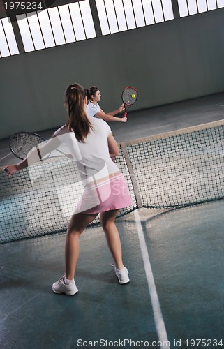 Image of young girls playing tennis game indoor