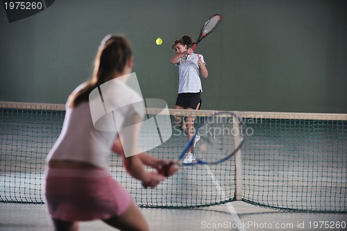 Image of young girls playing tennis game indoor