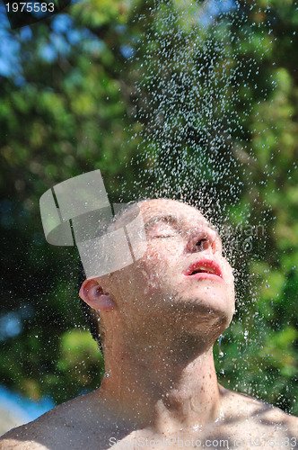 Image of young man relaxing under shower
