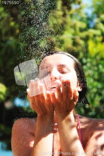 Image of beautiful woman washing and cleaning face under shower