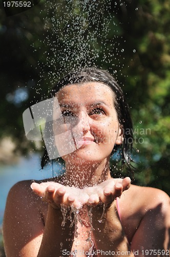 Image of beautiful woman washing and cleaning face under shower
