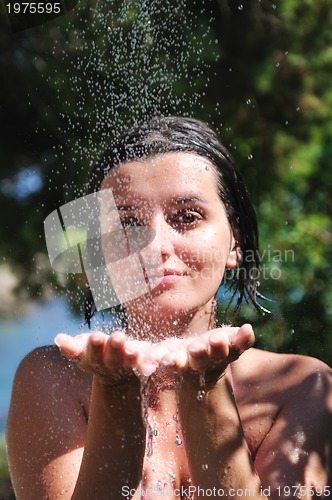 Image of beautiful woman washing and cleaning face under shower