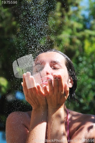 Image of beautiful woman washing and cleaning face under shower