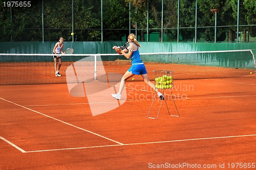 Image of Two young women playing tennis outdoors on Two young womwn playi