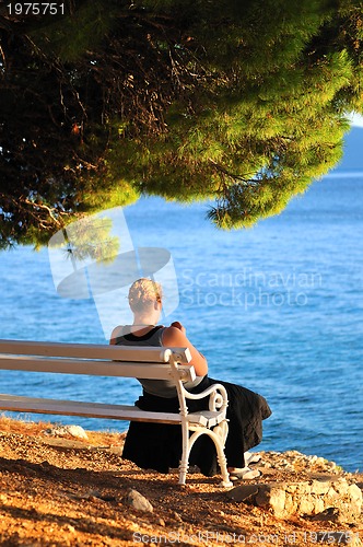 Image of Single woman sitting alone by the beach 