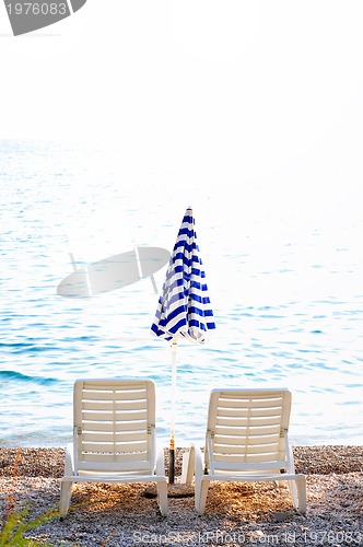 Image of empty chairs on beach with umbrella