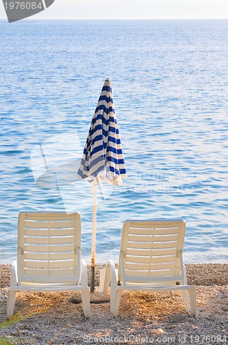 Image of empty chairs on beach with umbrella