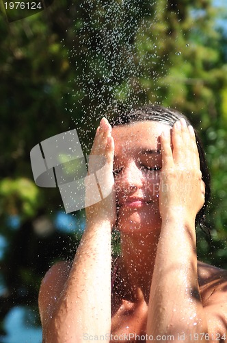 Image of beautiful woman washing and cleaning face under shower