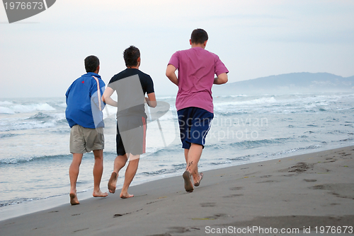 Image of three friends jogging at beach