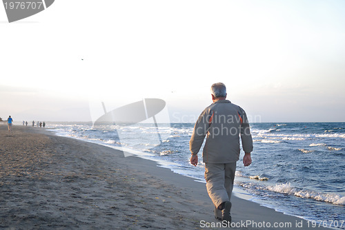 Image of lonely older  man walking on beach