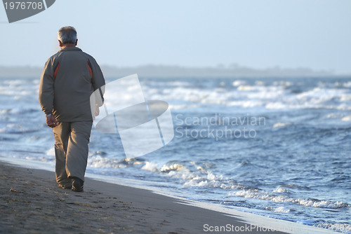 Image of lonely older  man walking on beach