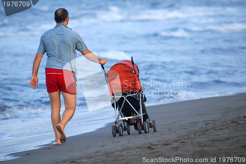 Image of father with stroller at early morning walking on beach