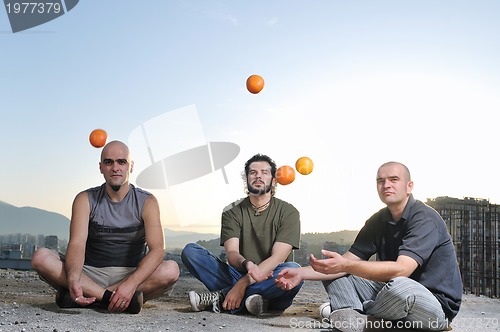 Image of three man outdoor play with orange fruit