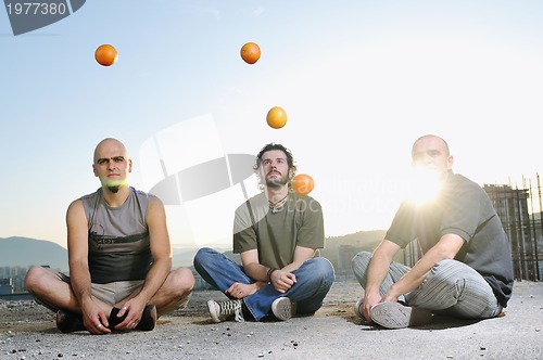 Image of three man outdoor play with orange fruit