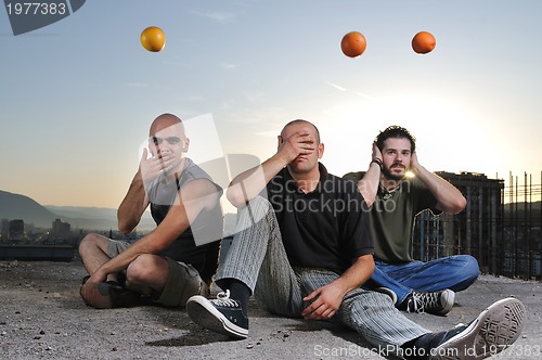 Image of three man outdoor play with orange fruit