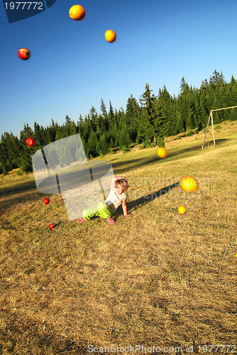 Image of happy girl throwing apple outside