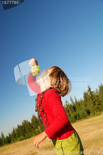 Image of happy girl with grape outside
