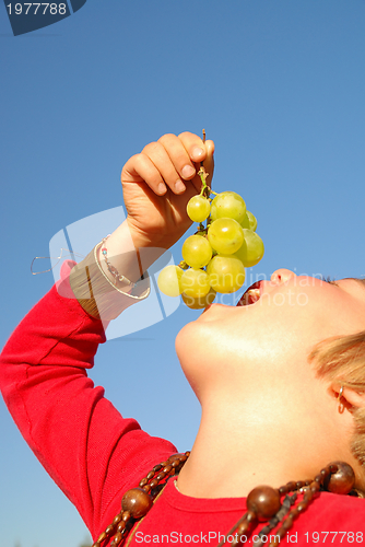 Image of happy girl with grape outside