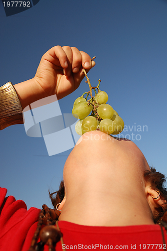 Image of happy girl with grape outside