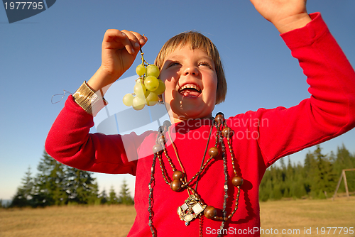 Image of happy girl with grape outside