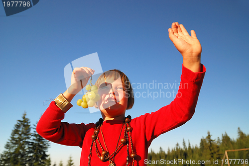 Image of happy girl with grape outside