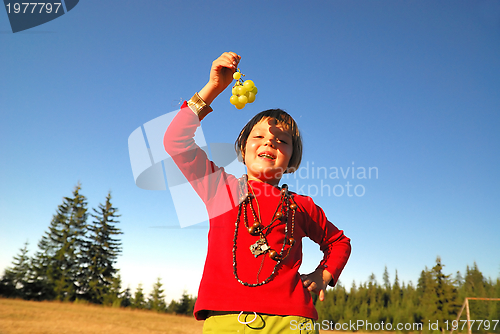 Image of happy girl with grape outside