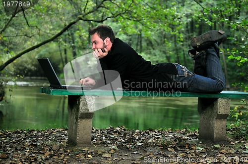 Image of young businessman working on laptop outdoor