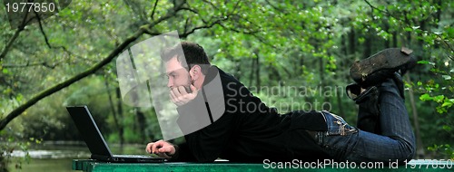 Image of young businessman working on laptop outdoor
