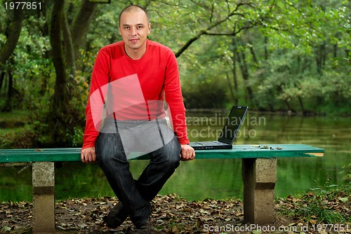 Image of young businessman working on laptop outdoor