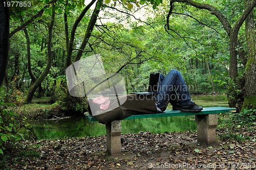 Image of young businessman working on laptop outdoor