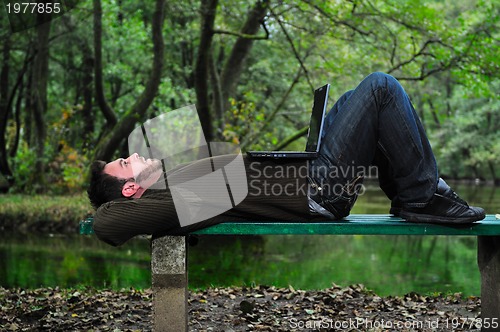 Image of young businessman working on laptop outdoor