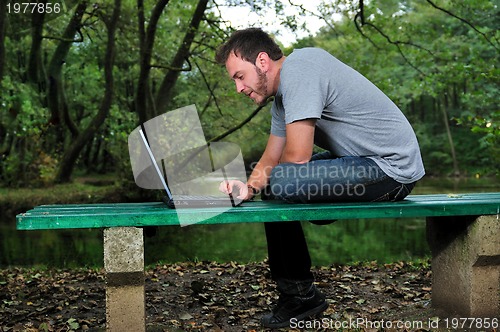 Image of young businessman working on laptop outdoor