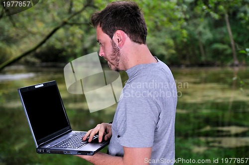 Image of young businessman working on laptop outdoor