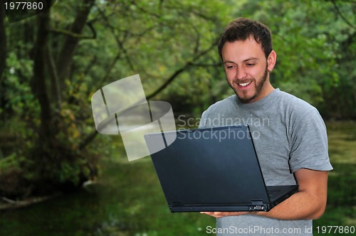 Image of young businessman working on laptop outdoor
