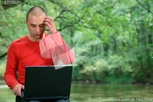 Image of young businessman working on laptop outdoor