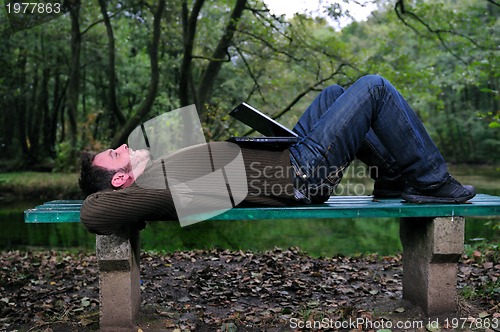 Image of young businessman working on laptop outdoor