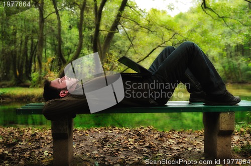 Image of young businessman working on laptop outdoor