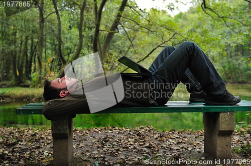 Image of young businessman working on laptop outdoor