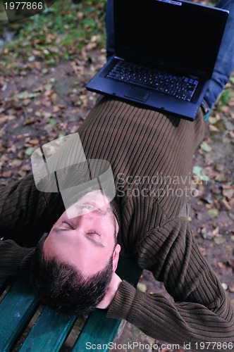 Image of young businessman working on laptop outdoor