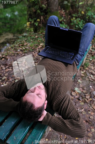 Image of young businessman working on laptop outdoor