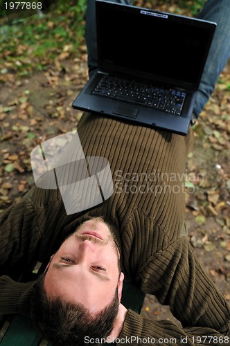 Image of young businessman working on laptop outdoor