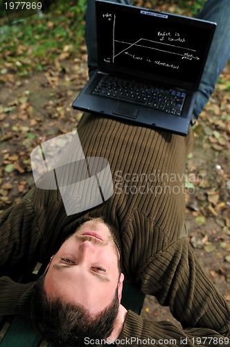 Image of young businessman working on laptop outdoor