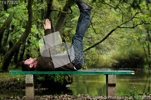 Image of young businessman with  laptop outdoor