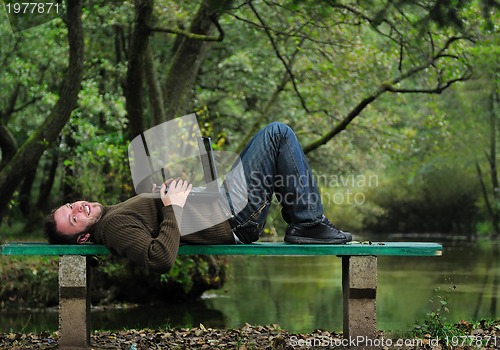 Image of young businessman working on laptop outdoor