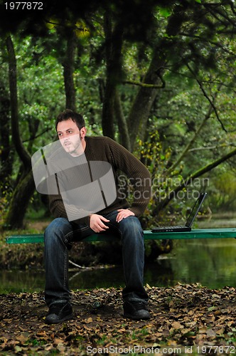 Image of young businessman working on laptop outdoor