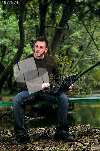 Image of young businessman working on laptop outdoor