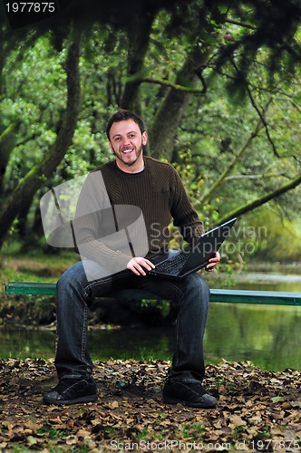 Image of young businessman working on laptop outdoor