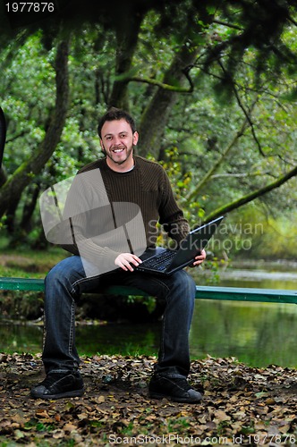 Image of young businessman working on laptop outdoor